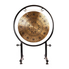 Buddha's Enlightenment Gong displayed on its black stand with sacred Buddhist symbols.