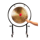 A person striking the Sacred Flower of Life Gong with a red felt mallet.